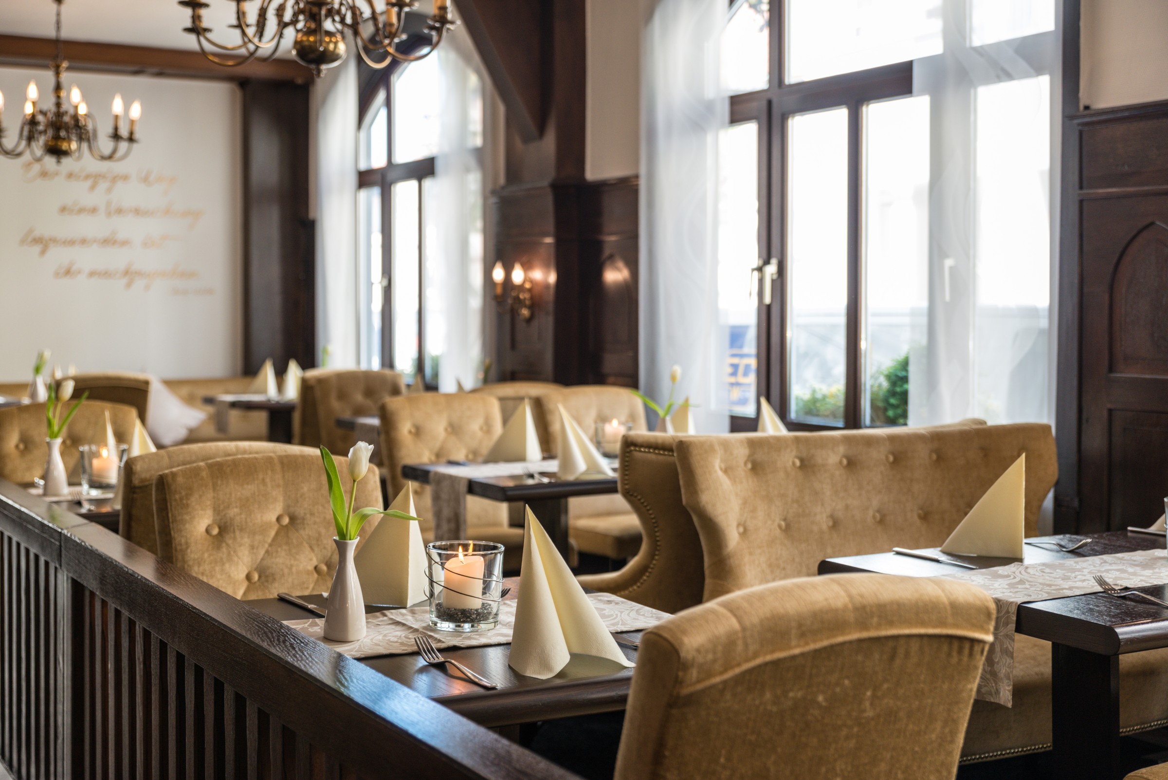 Set tables and gold-coloured upholstered armchairs by the window in Karl’s Esszimmer