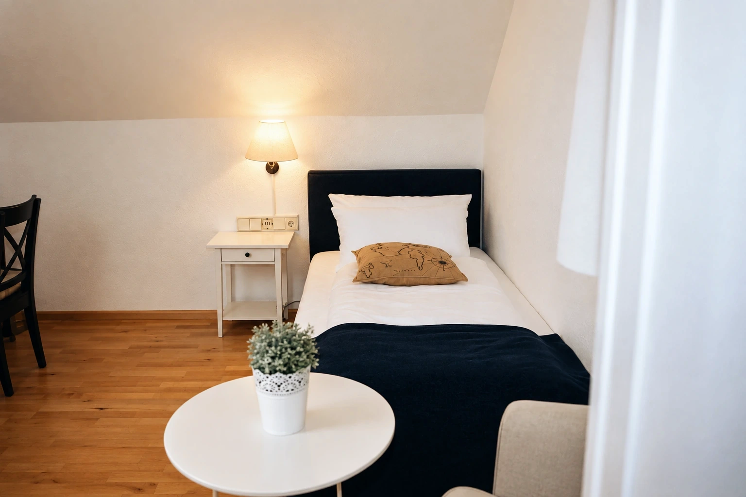 Einzelzimmer mit kleinem Tisch unter der Dachschräge