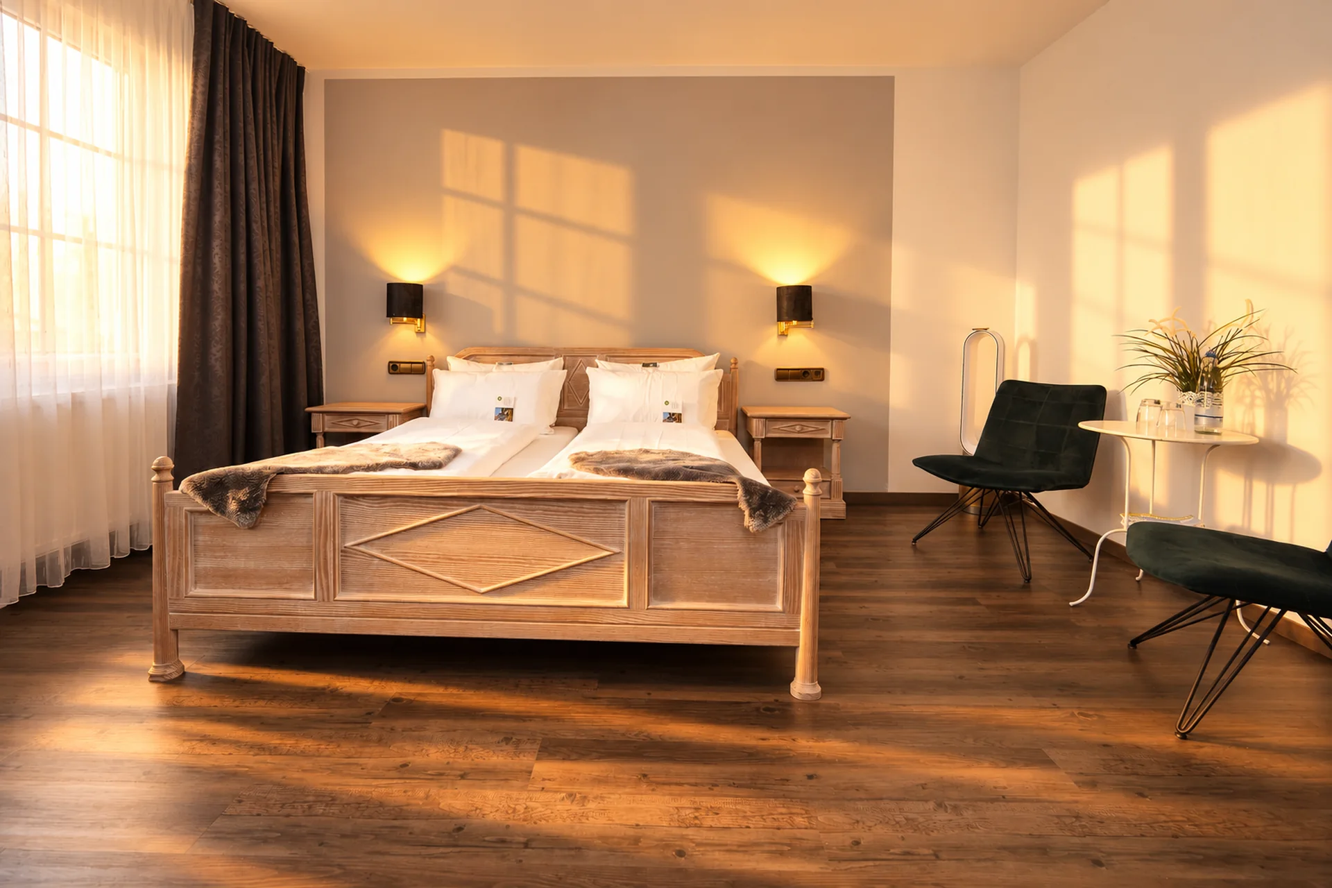 Komfortzimmer mit hellem Holzdoppelbett und dunkelgrüner Sitzgruppe